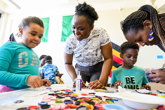 Instructors work with children on a project to educate about African culture