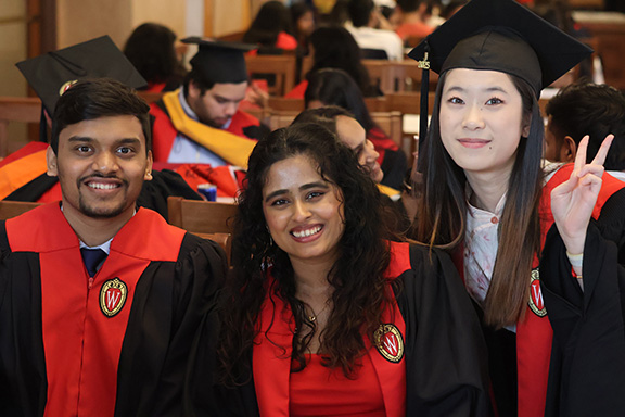 Smiling international students wearing commencement regalia