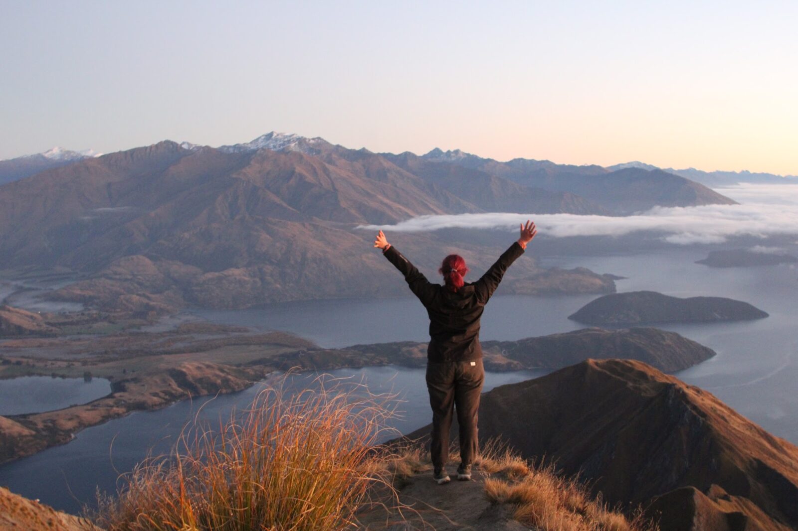 Student opening arms wide over Roys Peak in New Zealand